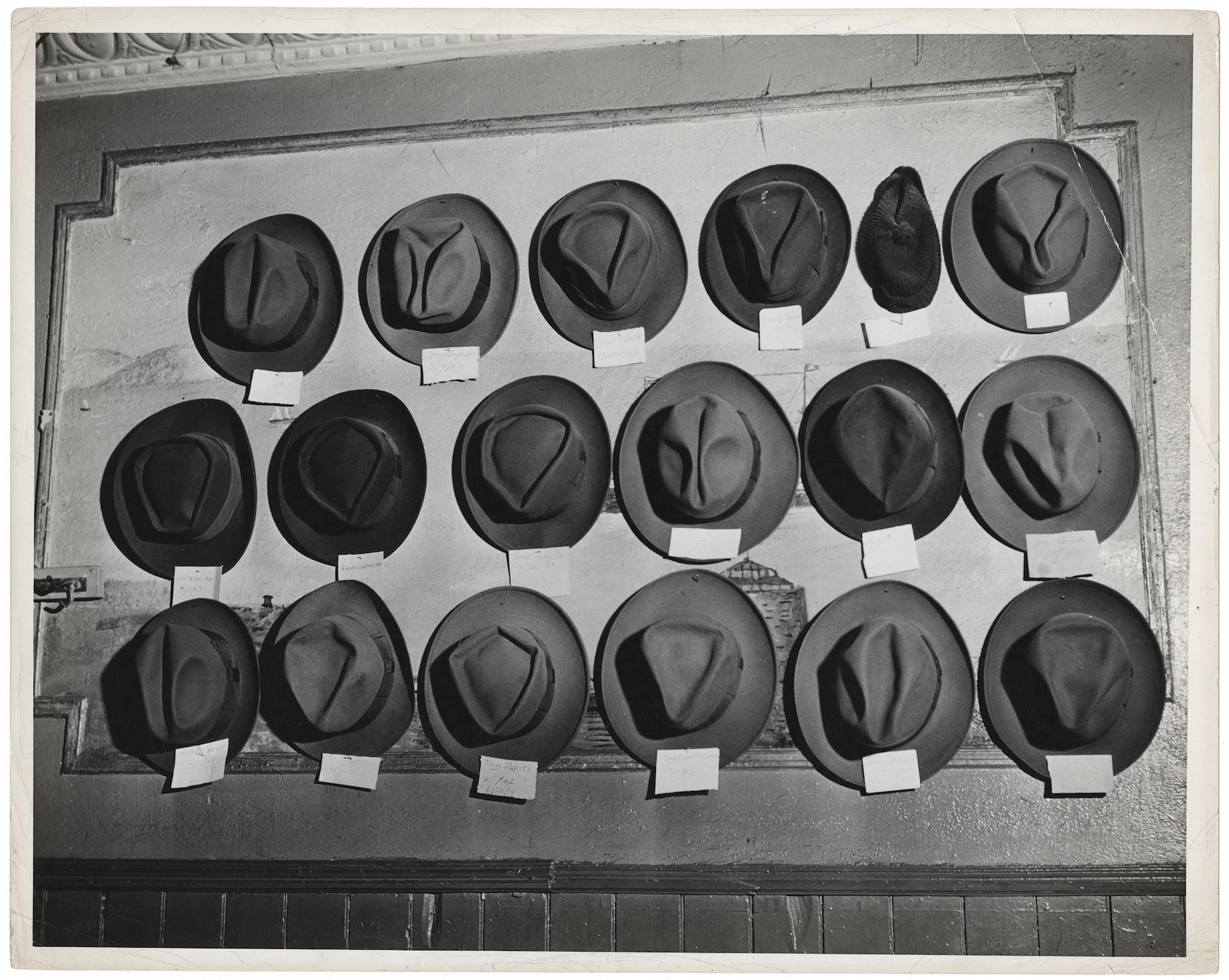 Hats hanging on a peg board with labels attached