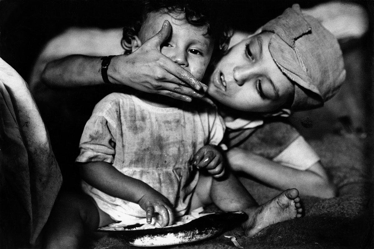 A boy feeds his younger brother by hand