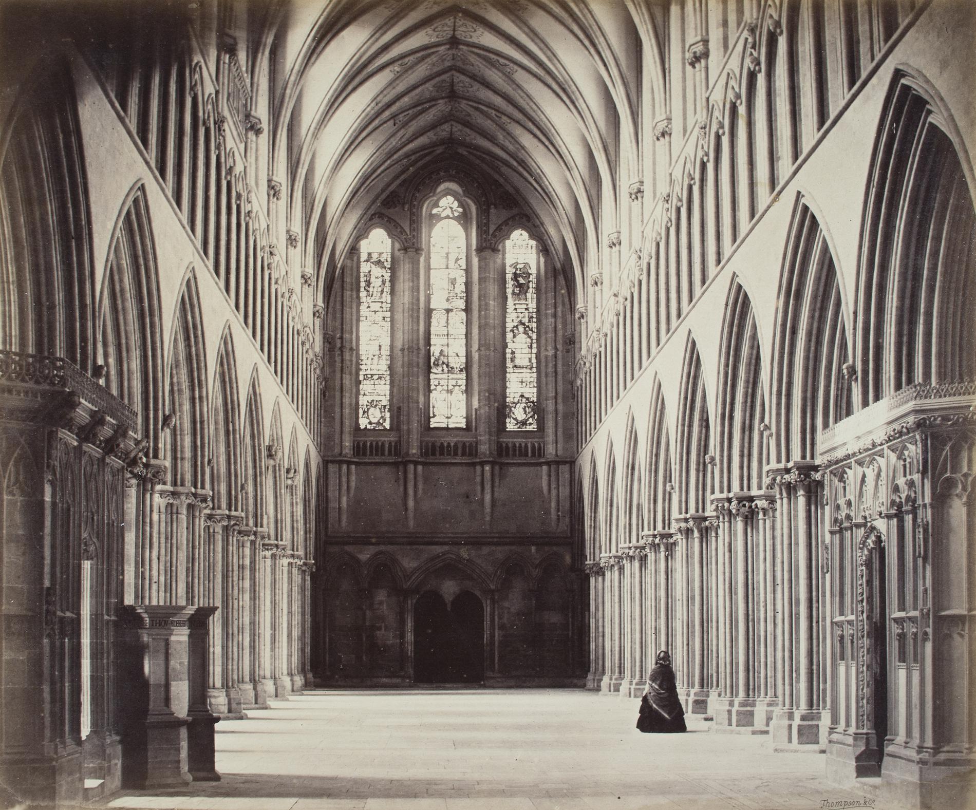 A woman in a dark dress stands in the great hall of a church. Photograph by Francis Bedford.