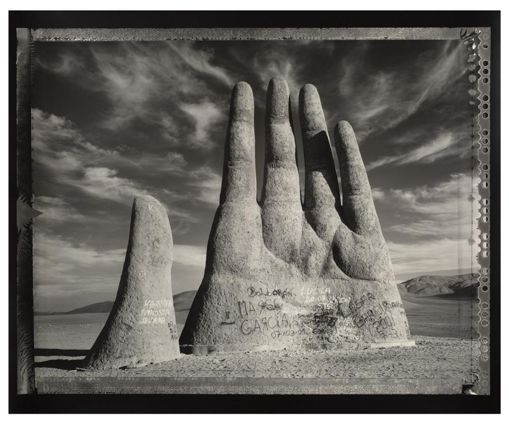 A rock formation shaped like a hand juts out of the ground