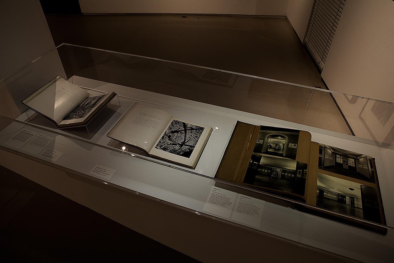 Books in a glass case, open to reveal photographs and text