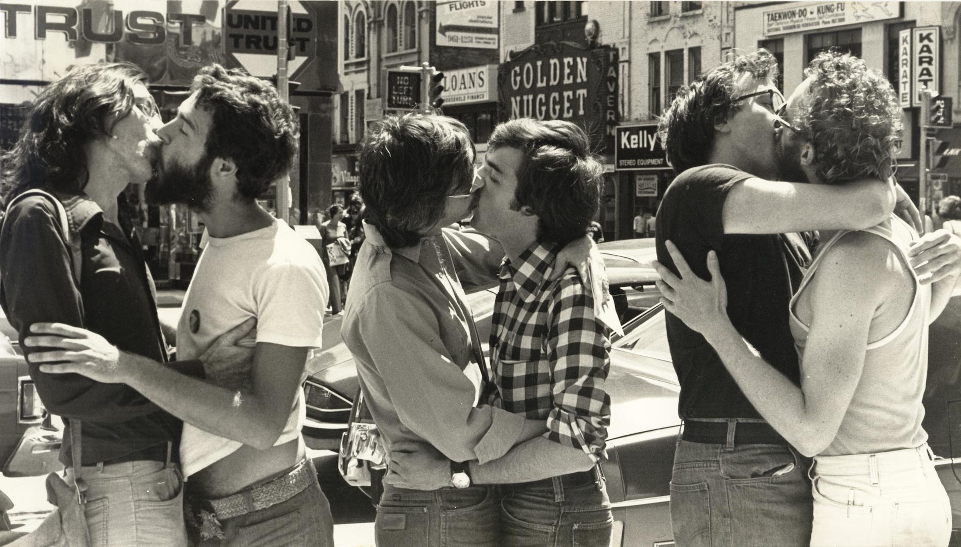Three same-sex couples kiss in the middle of the street
