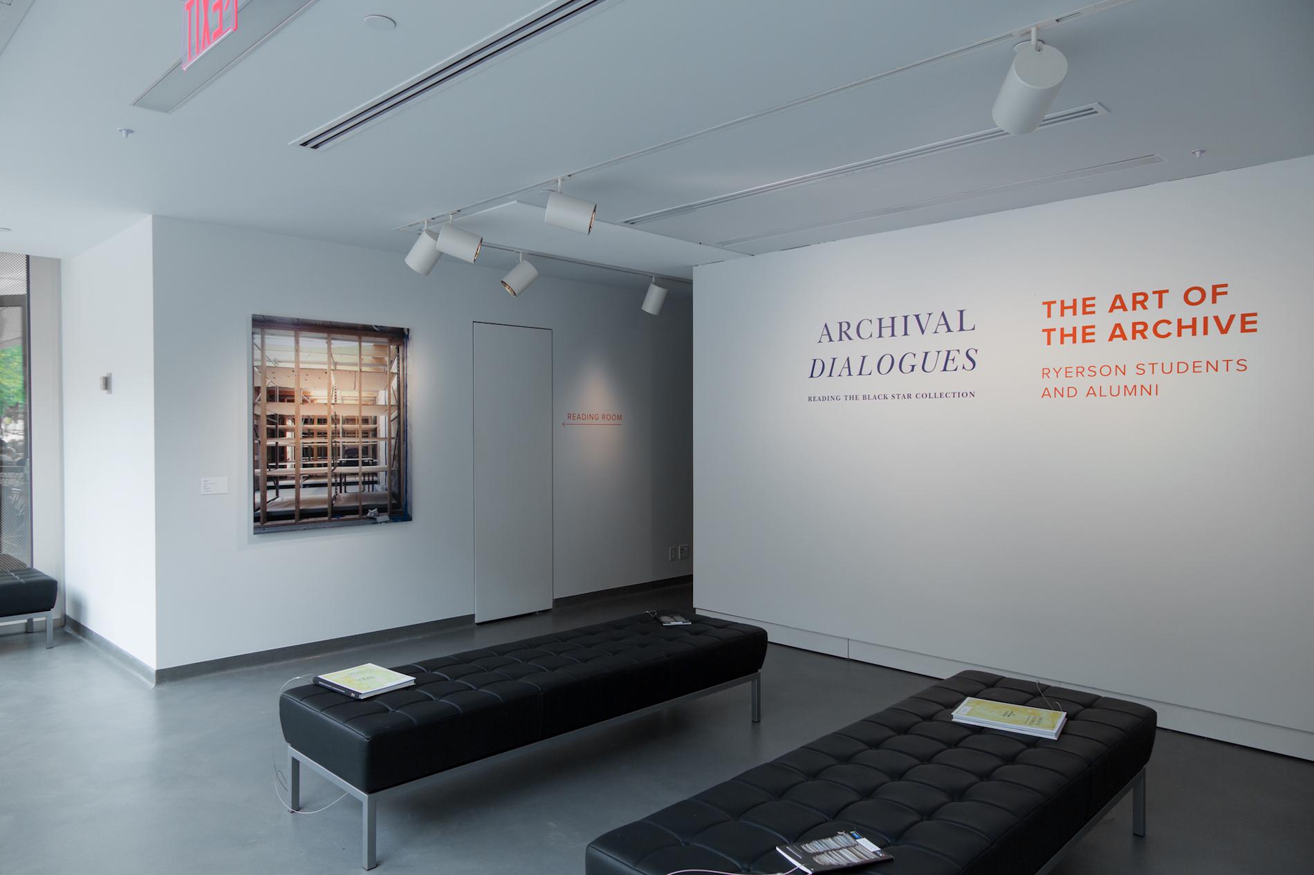 Two black benches sit in the center of the room, text on the wall reads "Archival Dialogues: Reading the Black Star Collection" and "The Art of the Archive: Ryerson Students and Alumni"
