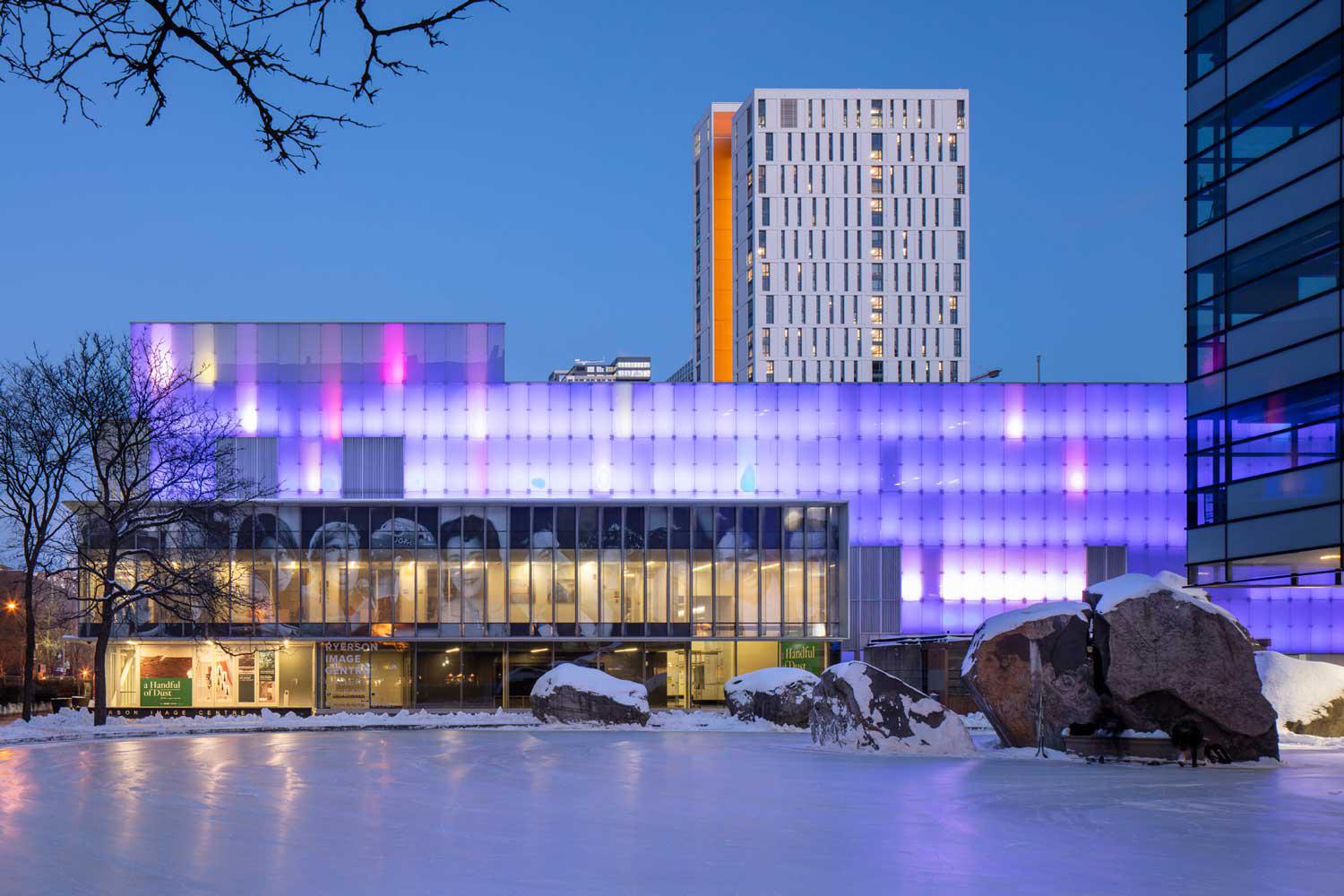 Exterior of the RIC at night with purple lights, showing Lake Devo in the foreground.