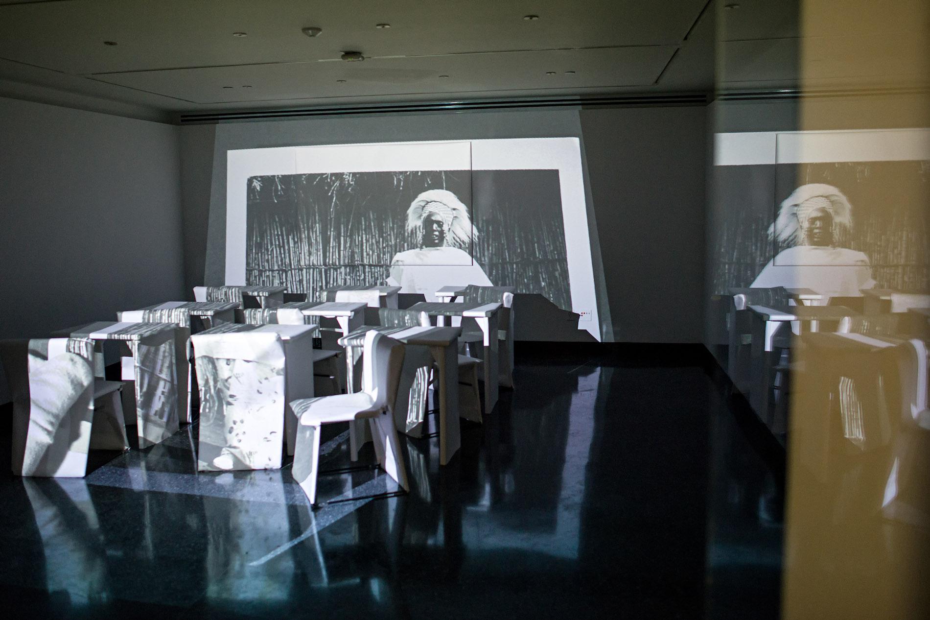 White chairs and tables in a dark room, an image projected on the wall