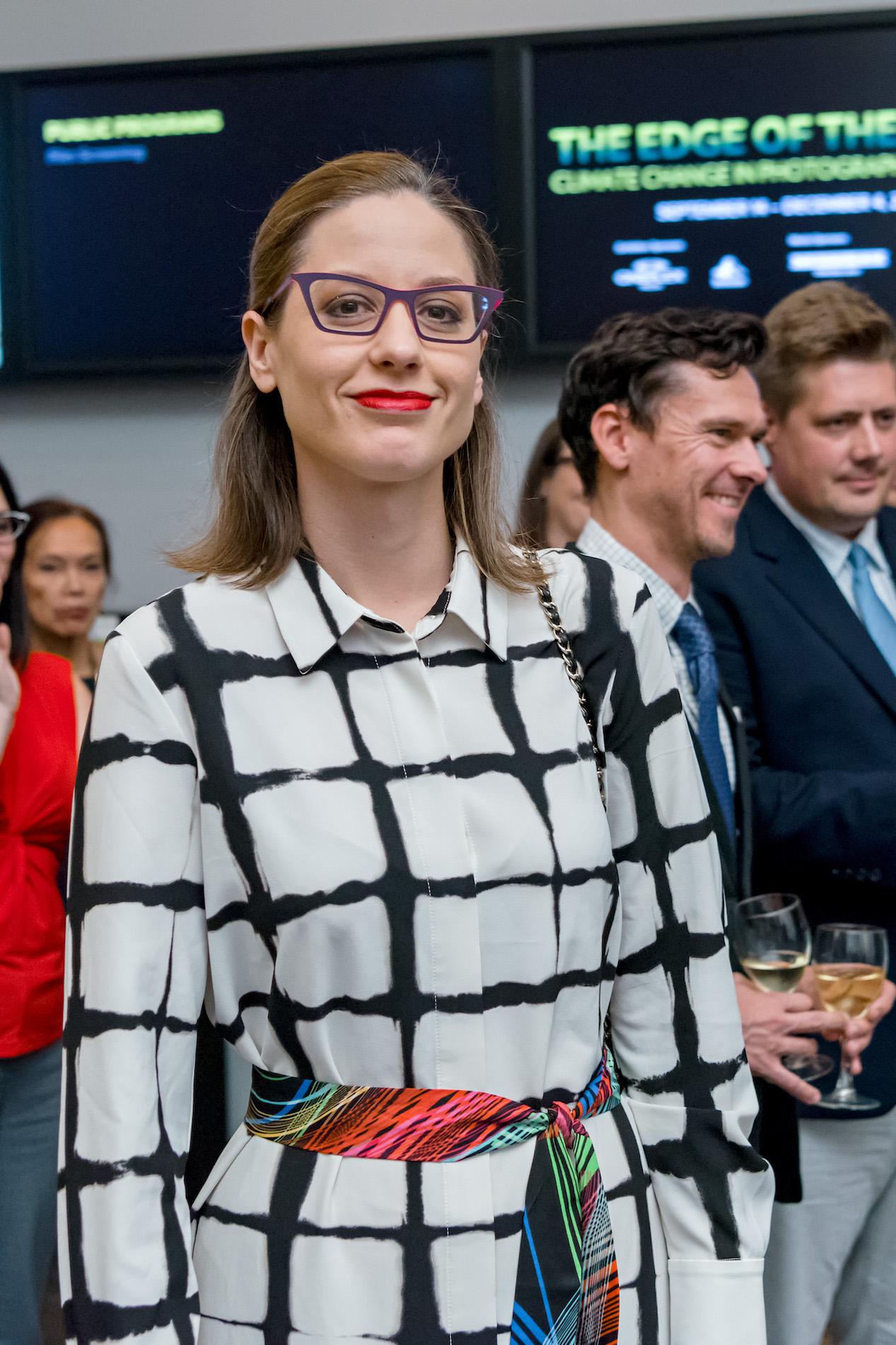 A woman wearing purple glasses and a black and white coat smiling