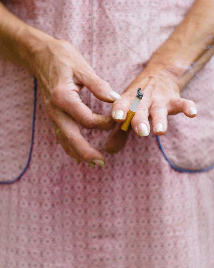 A close-up shot of a person's hands holding a cigarette