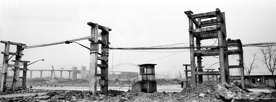 Deteriorated structures made of cement and steel with wires strung between them and rubble on the ground
