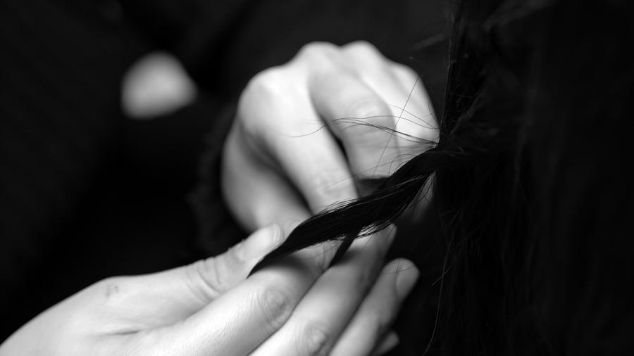 A hand braids dark hair