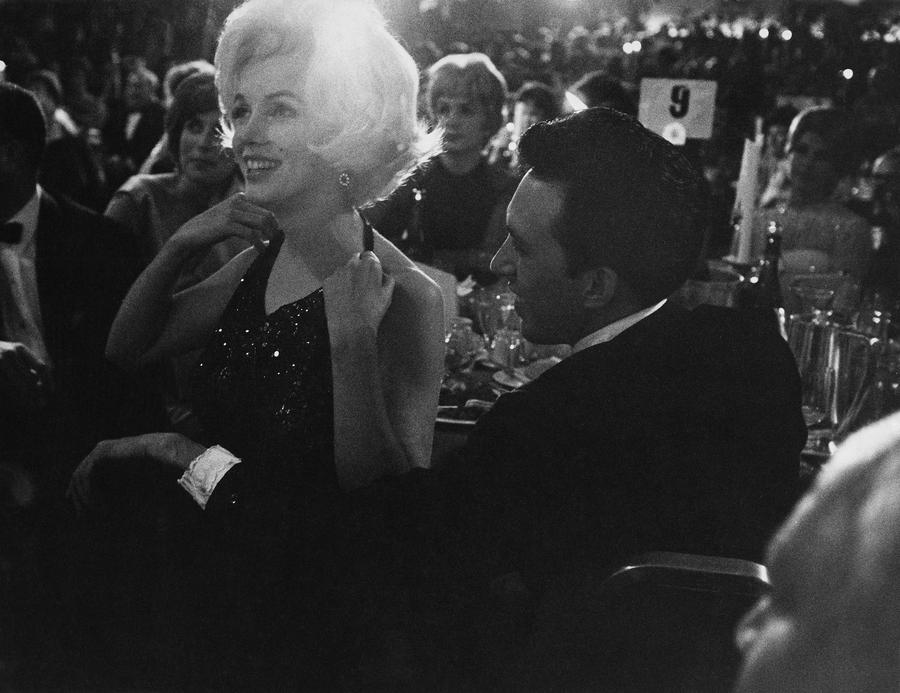 Marilyn Monroe in a black dress, smiling, at a formal event