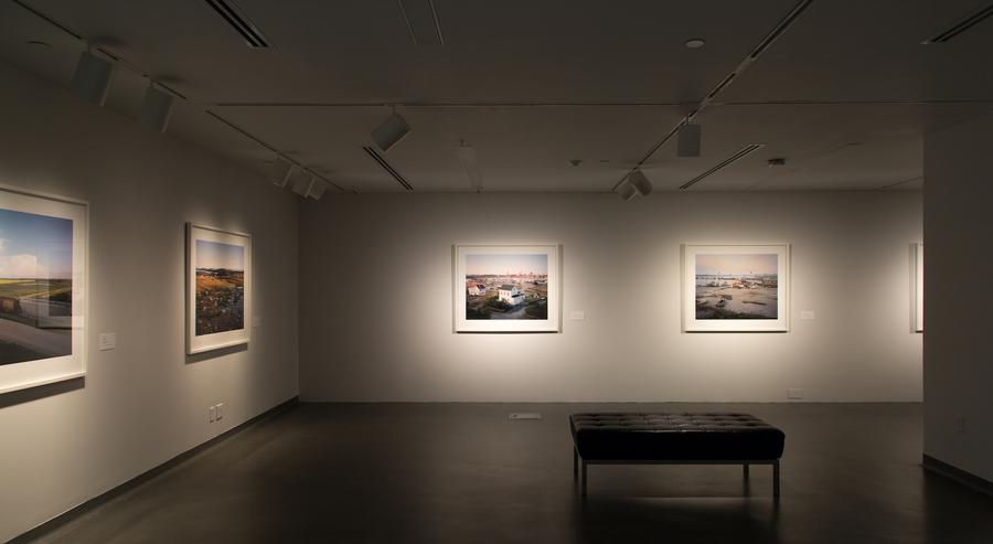Four photographs of rural Canada in white frames, a black leather bench in the centre of the gallery