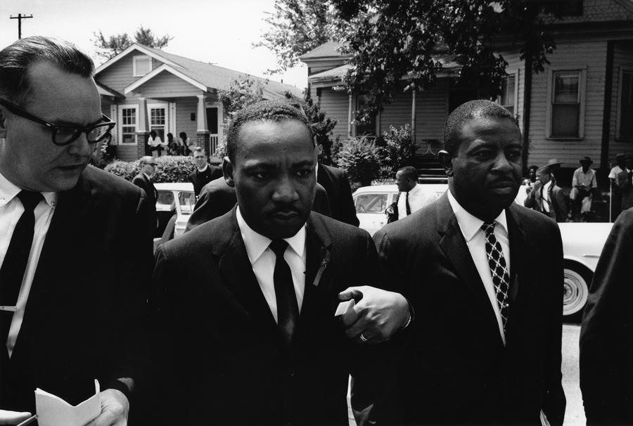 Martin Luther King Jr. walks between two other men, all three are wearing suits