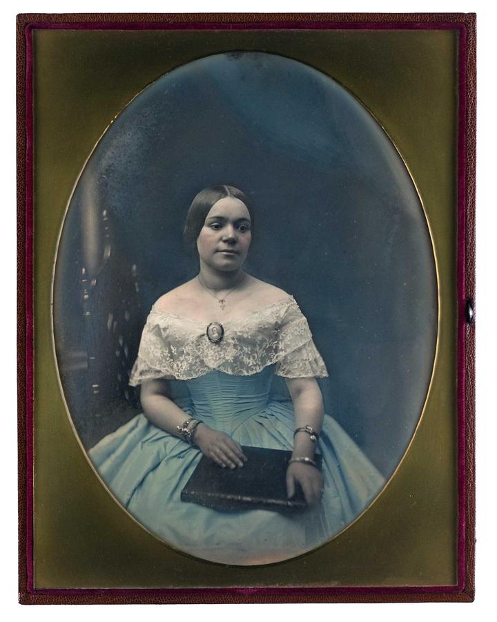 Girl seated, wearing a ballroom gown, and holding a purse