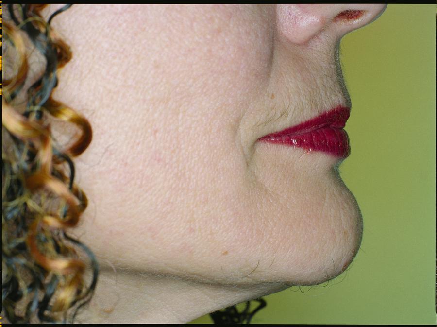 The side of a woman's face in front of a green background
