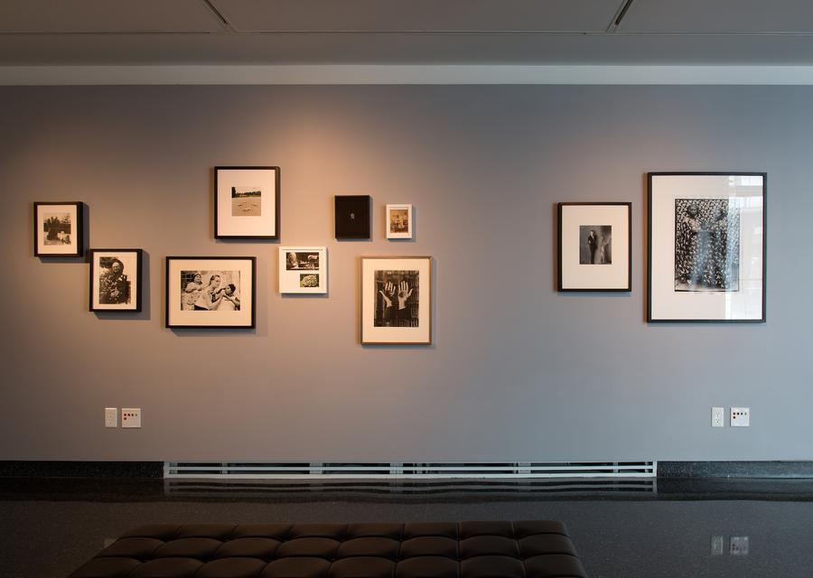 A cluster of photographs in different sized frames on a grey wall