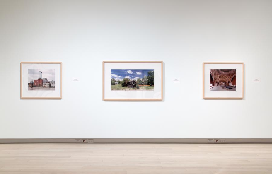 Three photographs in light brown frames on a white wall