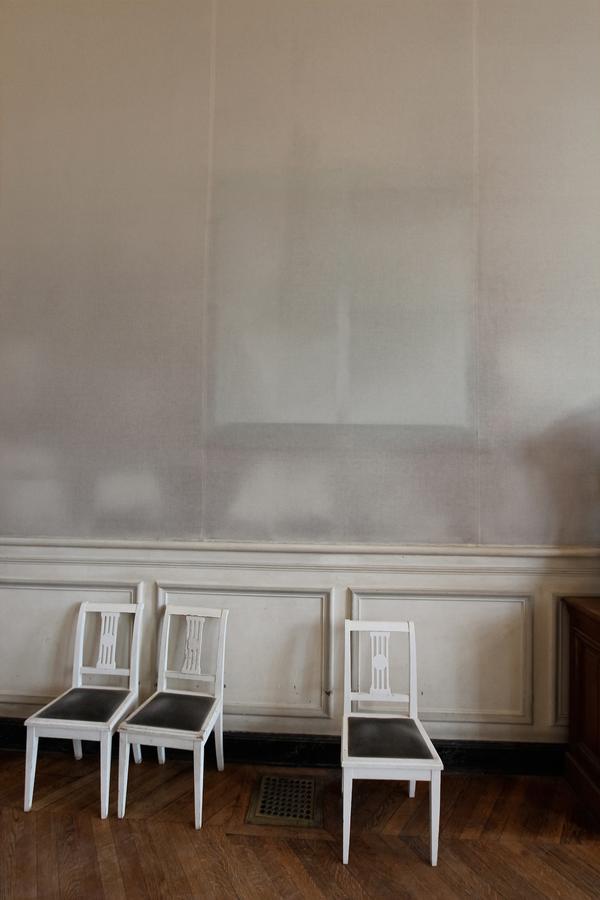 3 white chairs in front of a pink wall