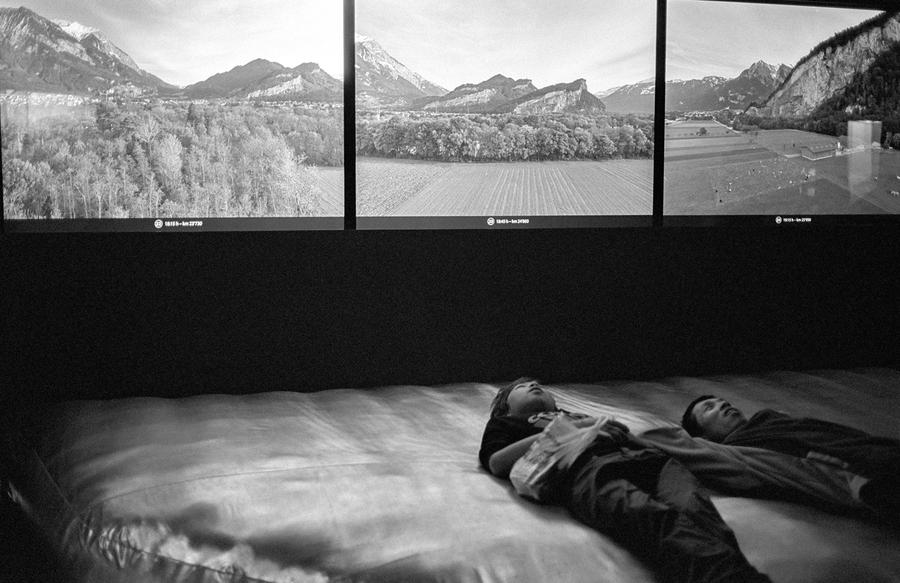 Two people laying down looking up at three landscape images.