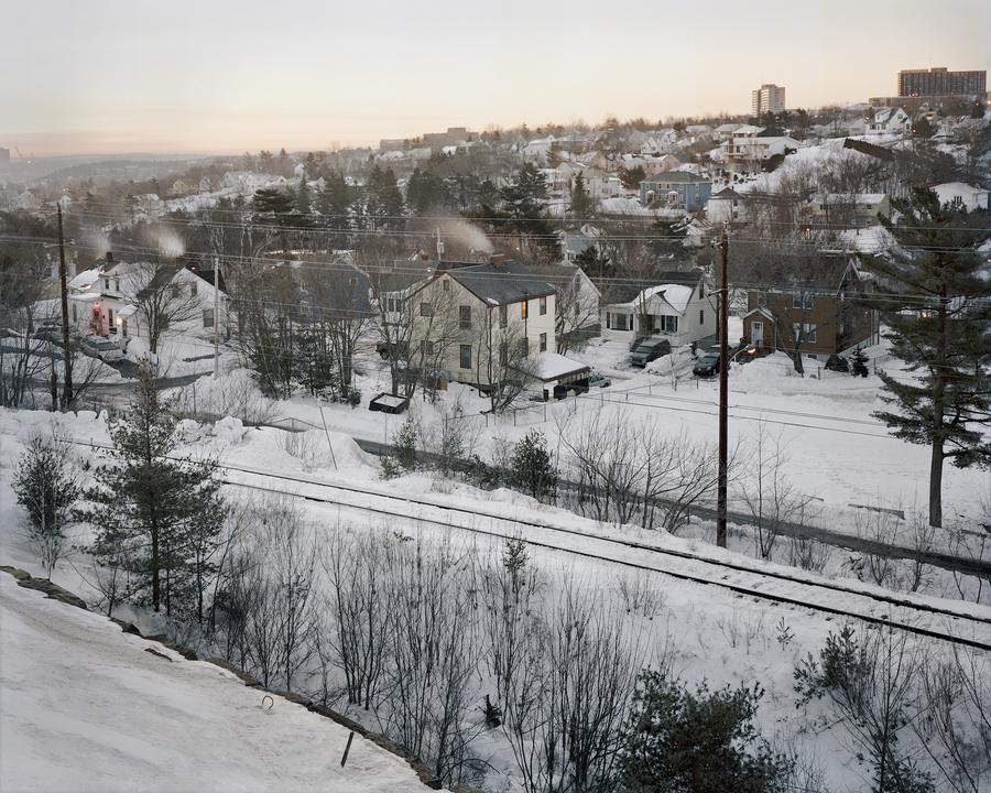 Train tracks beside a group of houses in a snowy town