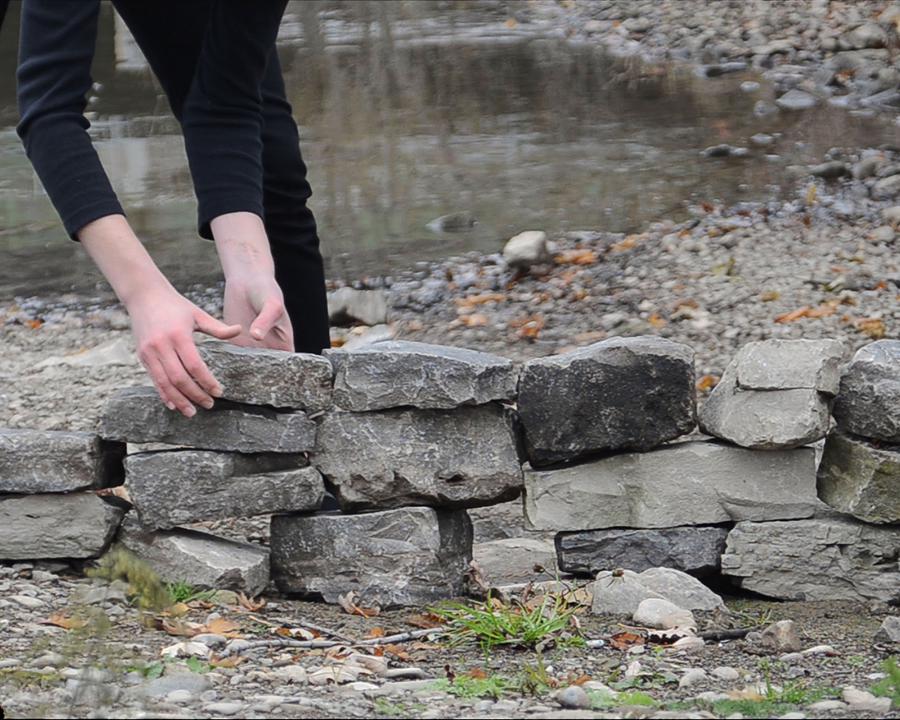 Hands stacking stone blocks into a wall