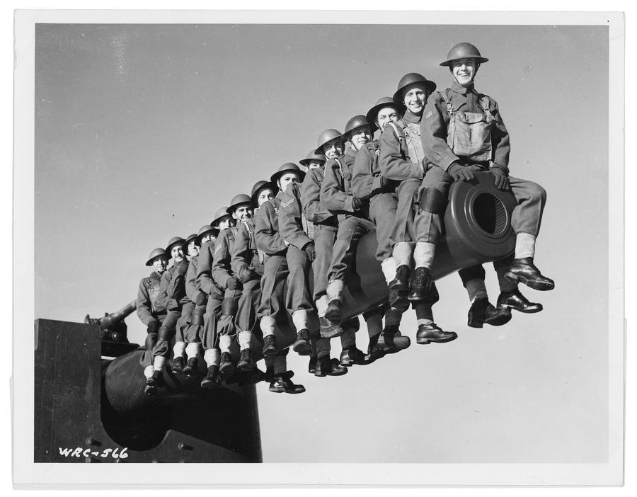 A group of sentries sit smiling atop a cannon