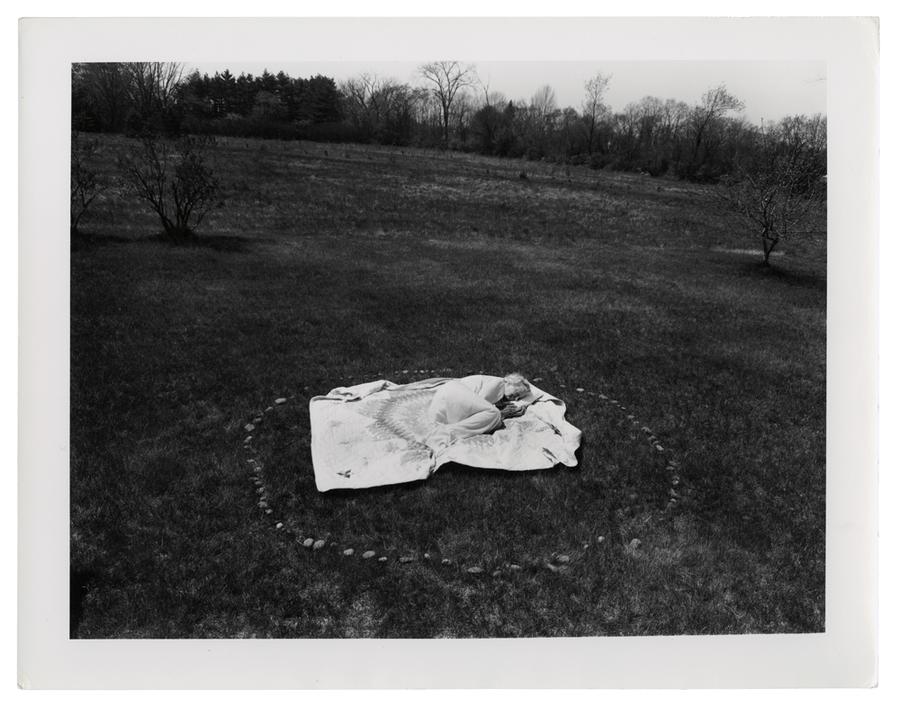 Grandmother sleeping on a blanket in a grassy field.