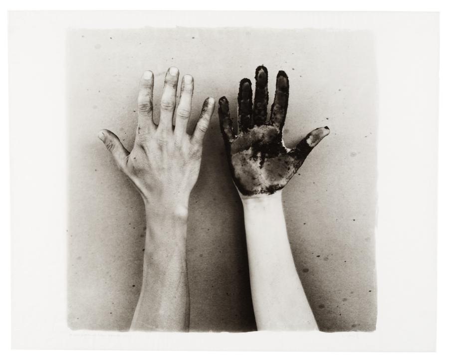 Image of outstretched arms - one hand facing down and the other facing up with the palm of the hand and fingers painted black.
