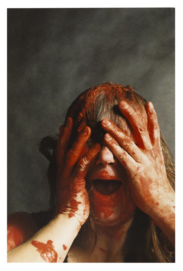 Photo of woman soaked in red substance covering her face.