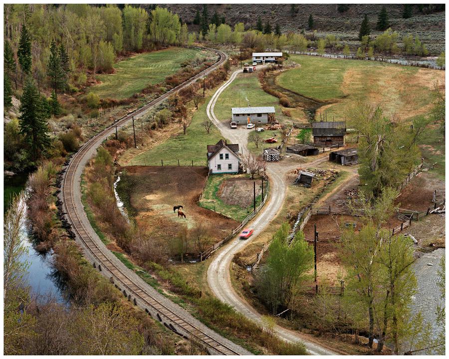 Photograph by Edward Burtynsky. A home next to a railroad and river.