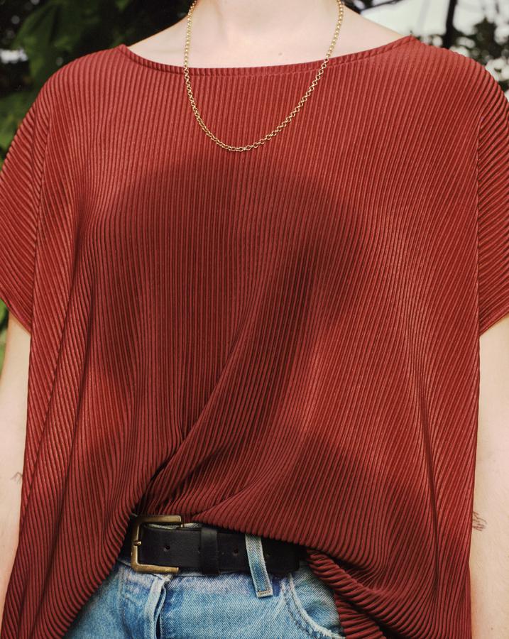 photo of a person's abdomen, wearing read shirt and gold chain