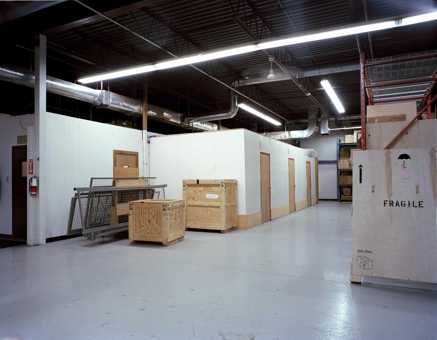 A warehouse with big crates and fluorescent lights