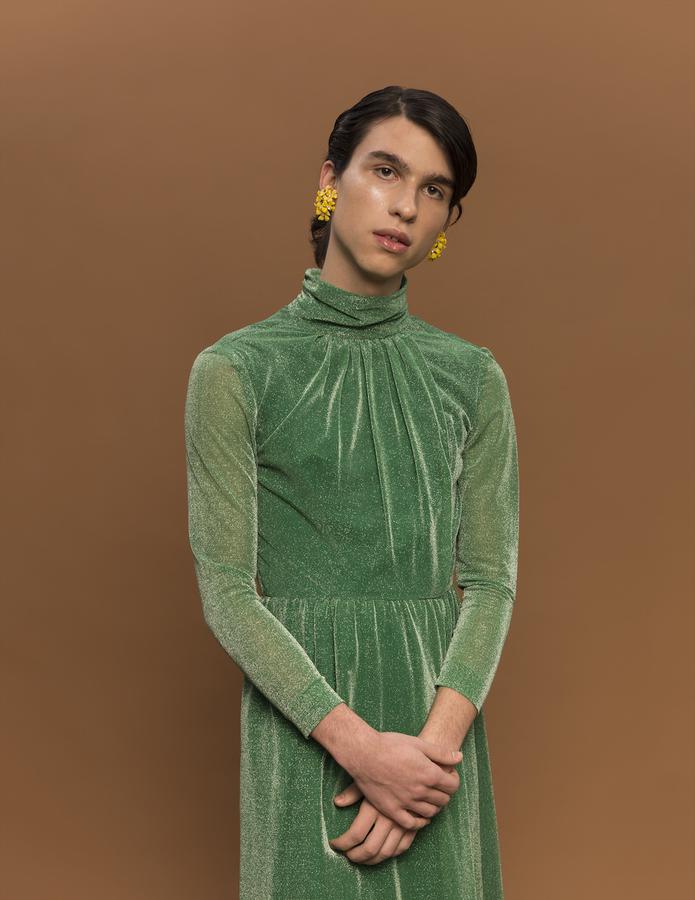 A young man wearing a green velvet dress