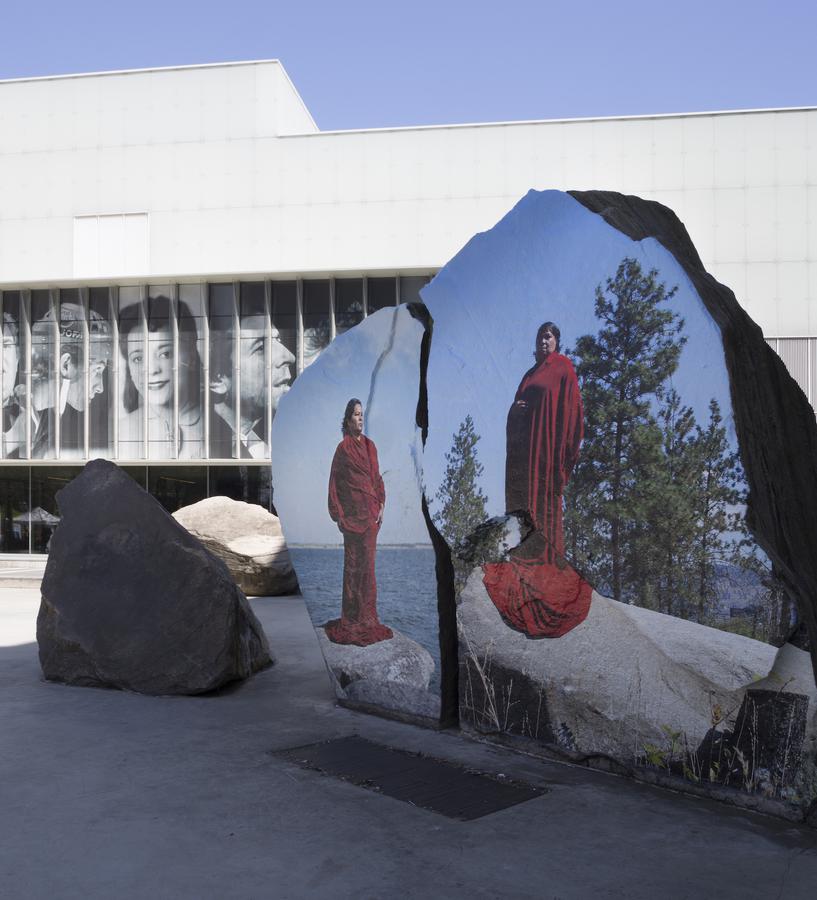 Two images of women in long red cloaks printed onto large rocks at Ryerson's Lake Devo