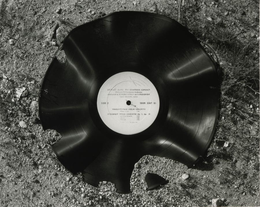 A bent and broken LP lies covered in sand