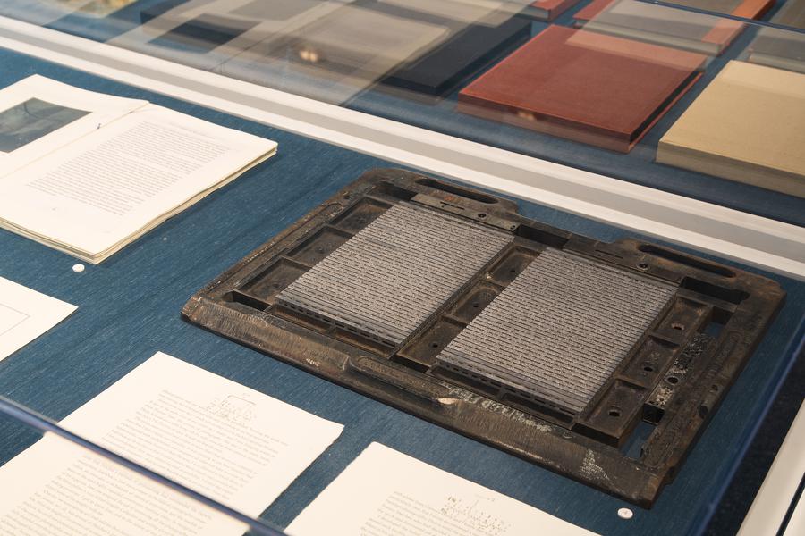 A display case containing books, pages, and plate sets