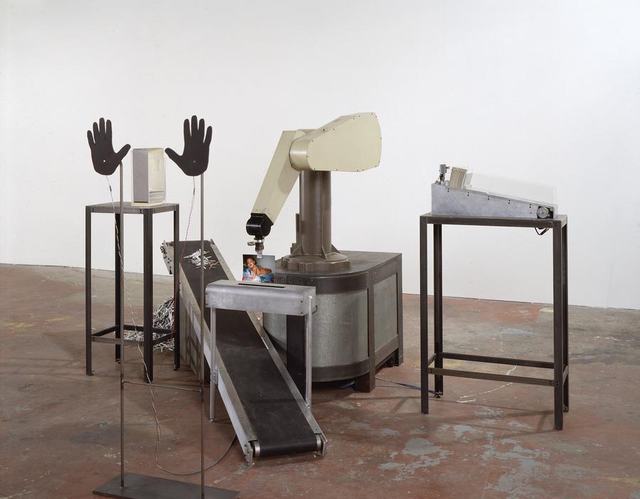 A pair of paper hands sit in front of a machine