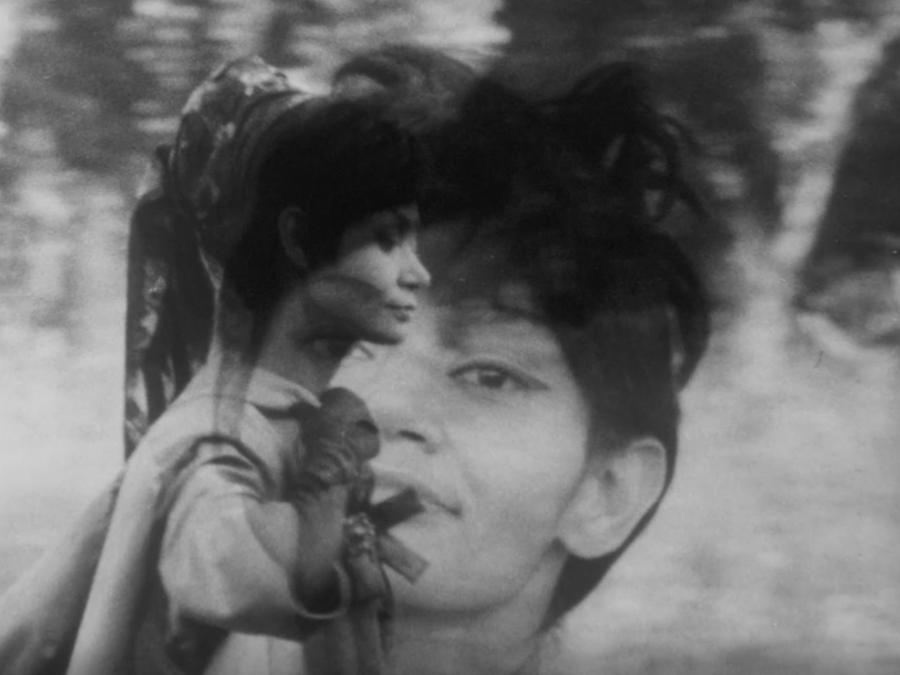 Two black and white photos overlayed with transparency. One features a woman's profile with a head wrap walking, the second image is of the same woman's face looking forward.