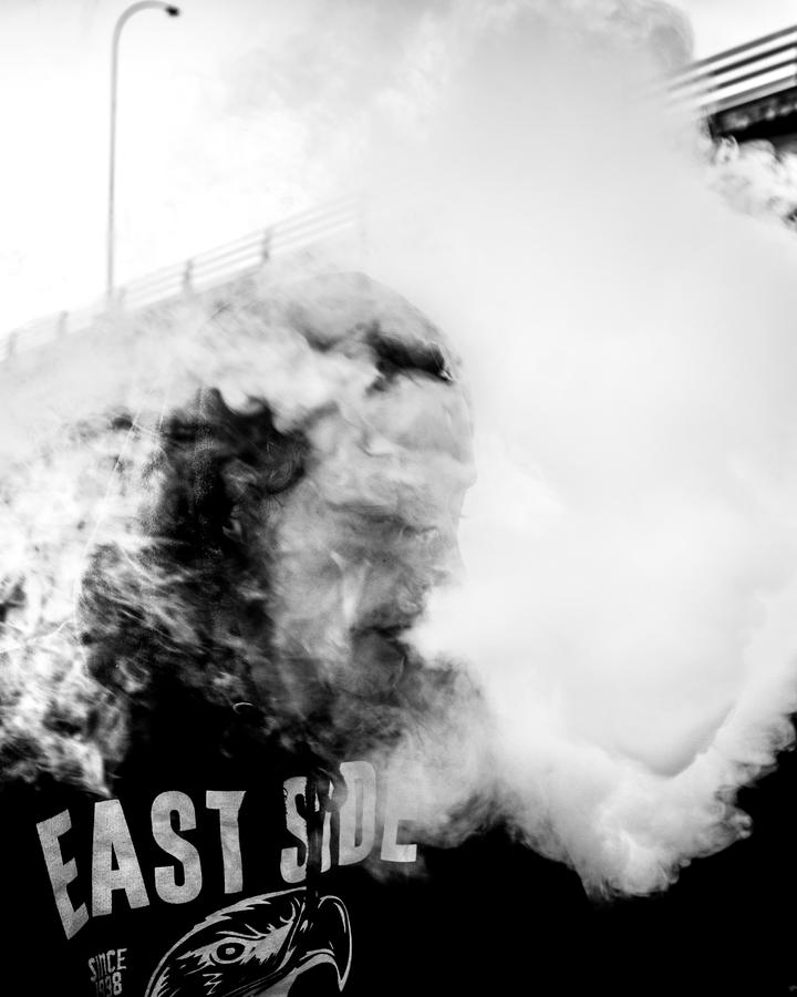 skateboarder moving through a cloud of vape smoke blown out of his mouth