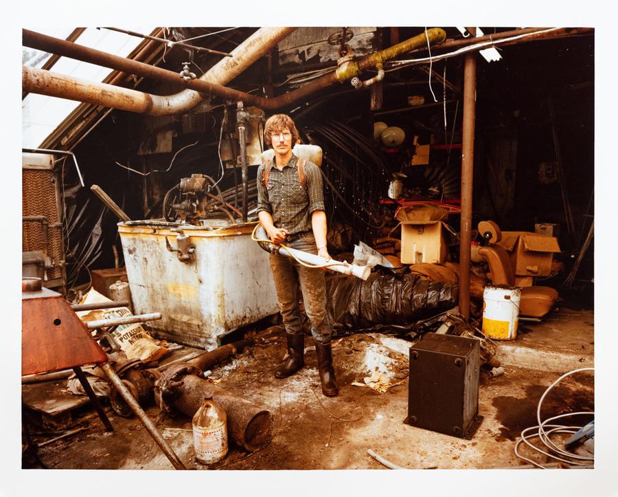 Photograph by Edward Burtynsky. A man holding a hose for spraying flowers.