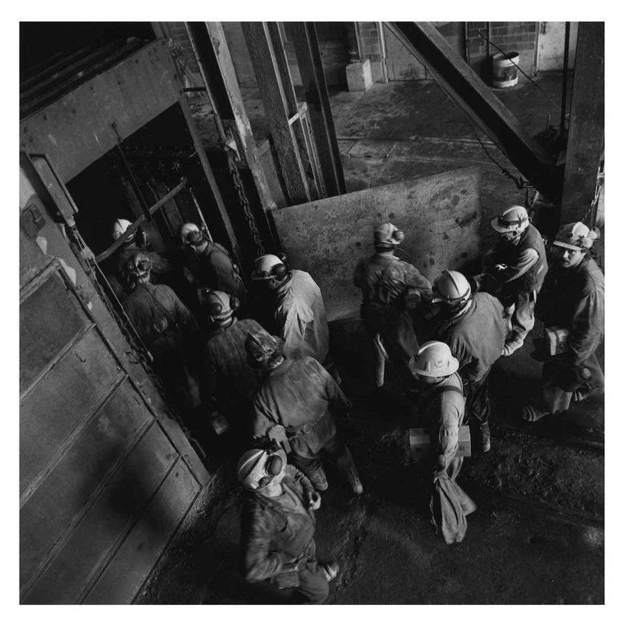 A photo taken from above showing a group of miners in hardhats entering a large doorway.
