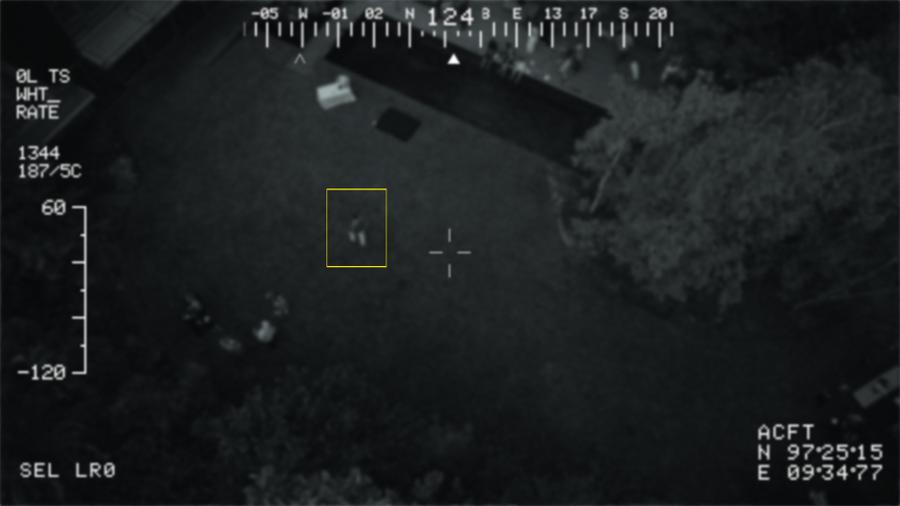 Drone photo of a man walking through a yard at night
