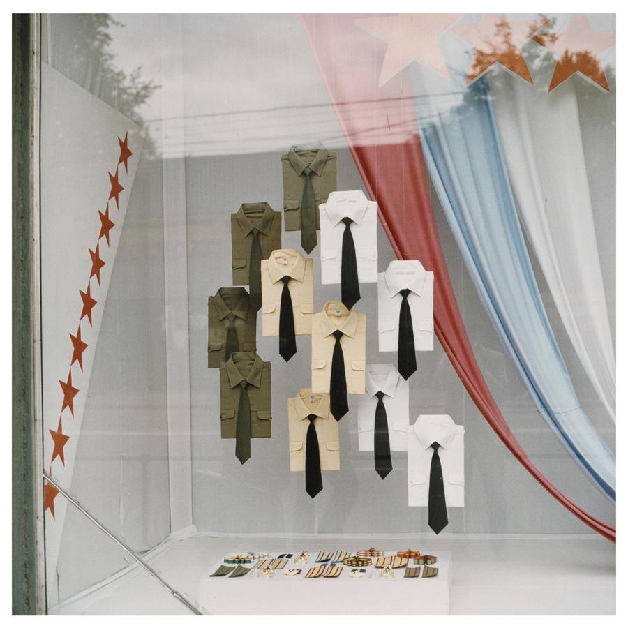 Military-style shirts with black ties hang in a shop window in Moscow.
