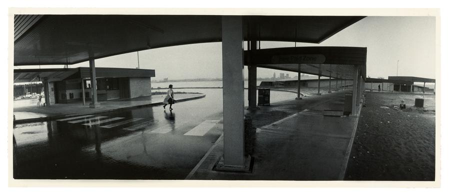 A foggy scene of a lone woman crossing the road at a terminal building
