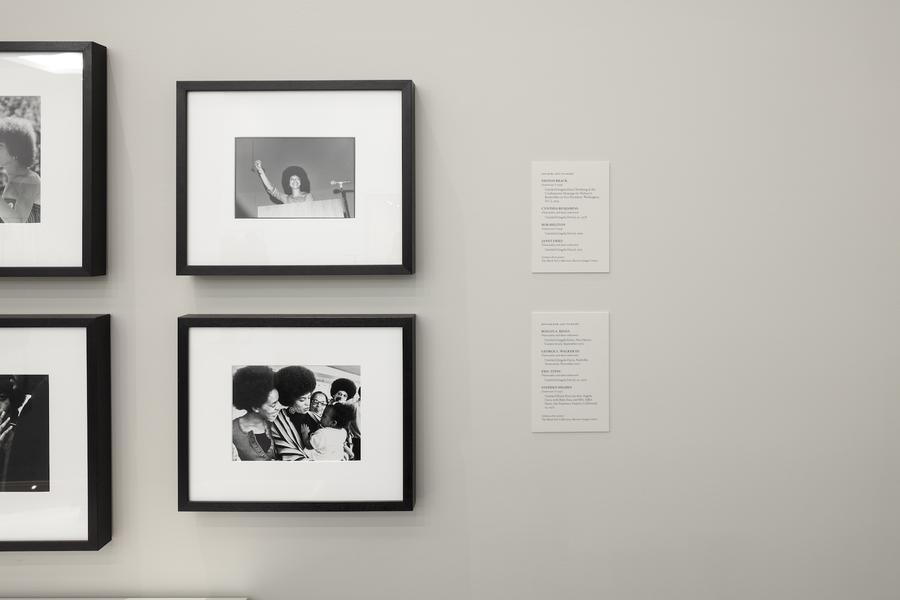 Two framed photographs, the top of a woman smiling at a podium, the bottom of a group of women smiling