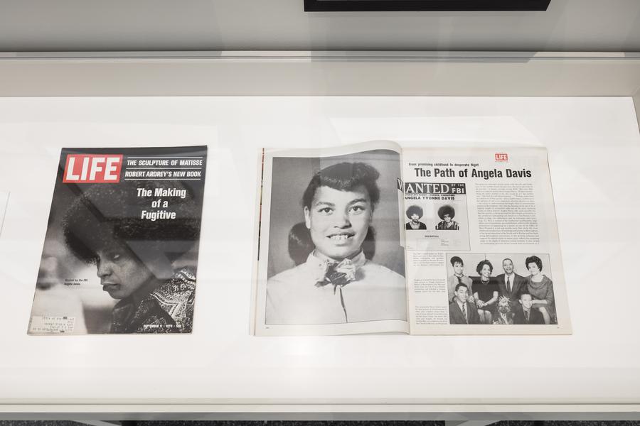 2 magazines in a display case. On the left, the cover of Life magazine, text reads "The Making of a Fugitive". On the right, a magazine open to a page reading "The Path of Angela Davis"