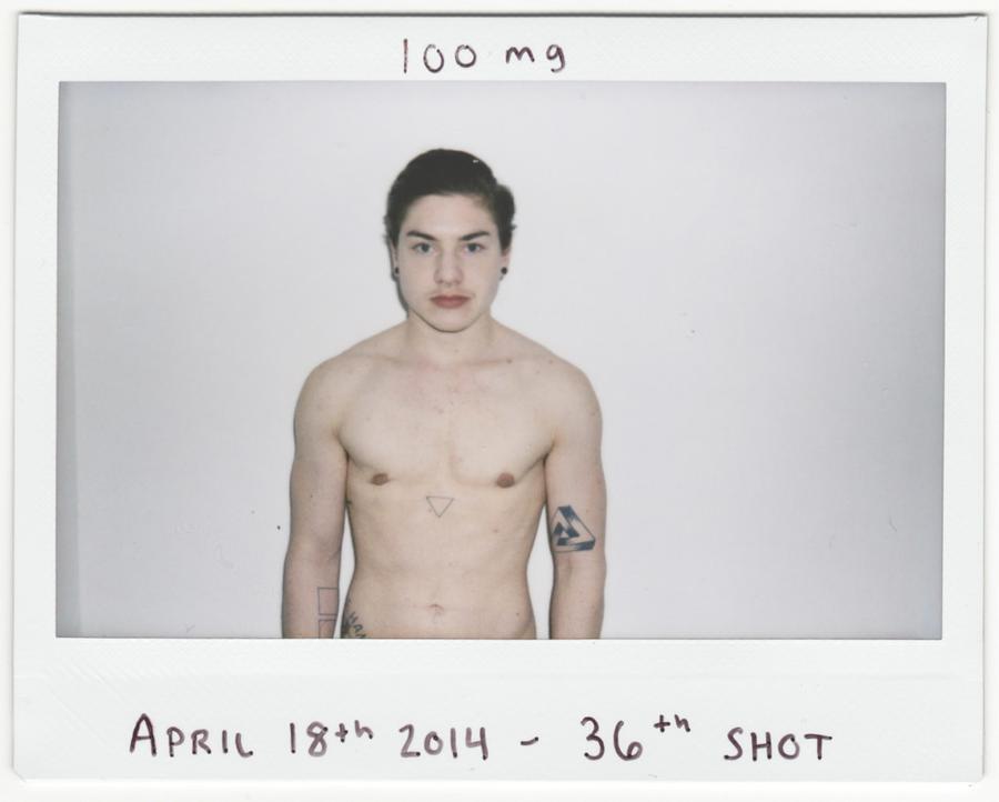 A shirtless man in front of a white wall staring at the camera. The handwritten text reads "100 mg. April 18th 2014. 36th shot."