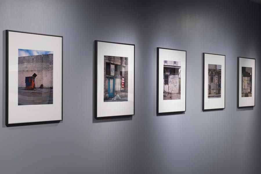 Square photographs framed with a wide white mat on a grey wall