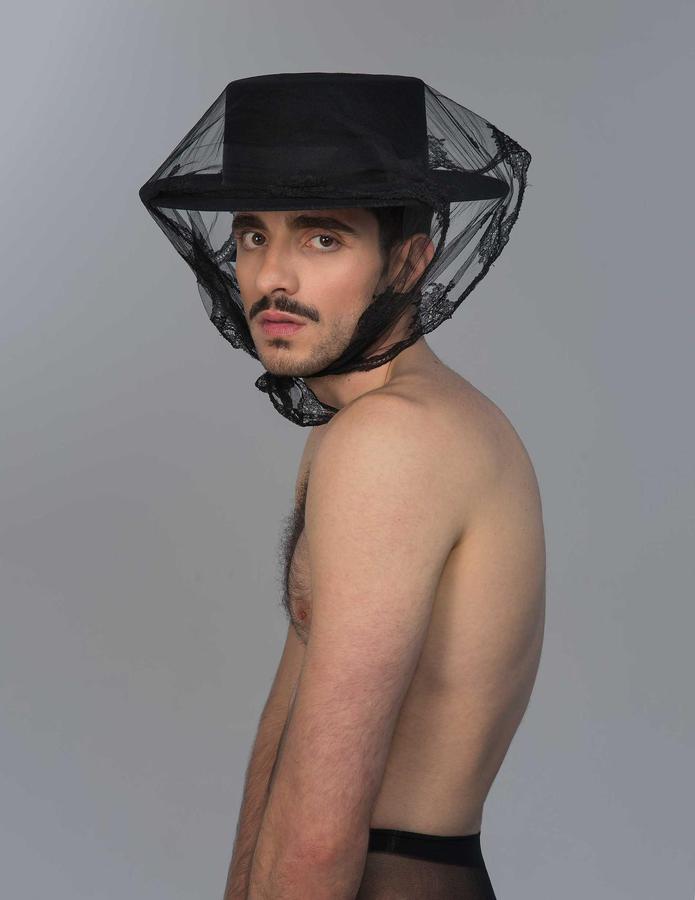 A young man posing for the camera wearing a hat