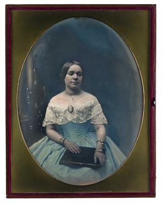 A girl seated, wearing a ball gown, with a purse in her hands