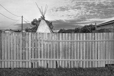 The top of a tipi peaks out above a wooden fence